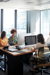 Four female creative colleagues working together in an office, vertical, crop