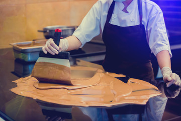 cook woman is mixing chocolate cream with professional chocolate spatula in the chocolate shop. melted dark chocolate.