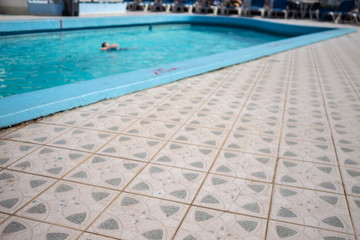 Tiled poolside and swimmer in the background