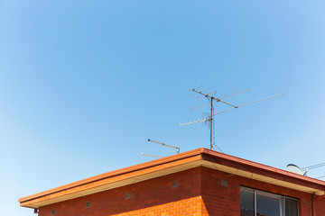 Analogue tv antennas perched on top of red retro brick house.