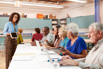 Group Of Retired Seniors Attending IT Class In Community Centre With Teacher