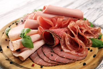 Food tray with delicious salami, pieces of sliced ham, sausages,salad and vegetable. Meat platter with selection