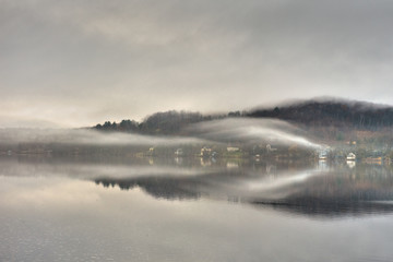 Early morning fog on the lake near a village. 