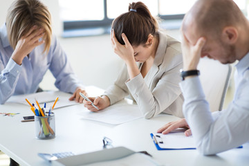 business, failure and people concept - stressed colleagues team with papers at office meeting