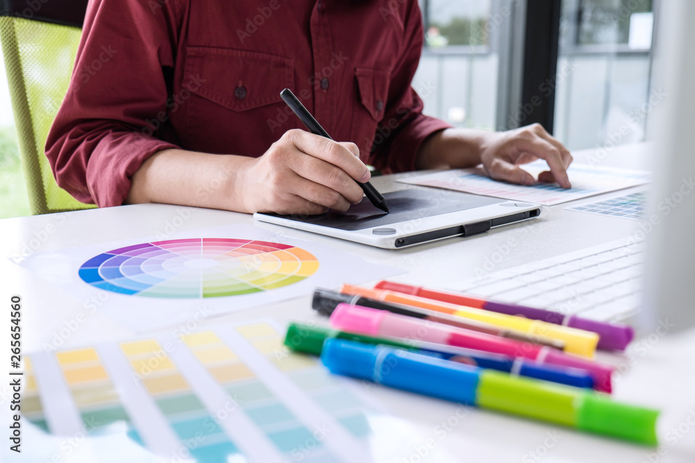 Poster image of female creative graphic designer working on color selection and drawing on graphics tablet 
