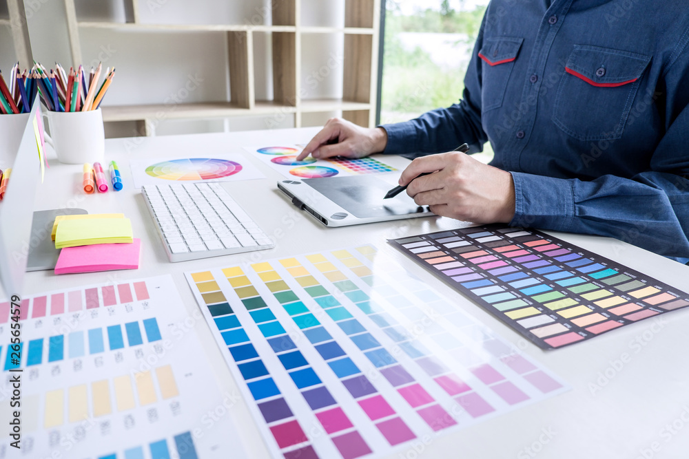 Aufkleber Image of male creative graphic designer working on color selection and drawing on graphics tablet at workplace with work tools and accessories