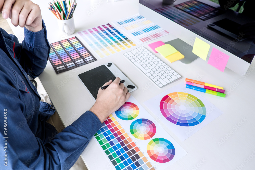 Poster male creative graphic designer working on color selection and color swatches, drawing on graphics ta
