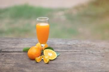  Orange juice in a glass and orange slices cooked on an old wooden table