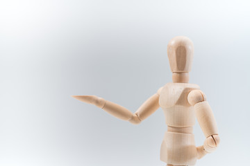 Wooden dummy proudly presents some invisible thing, isolated on white background, copy space for your object or text