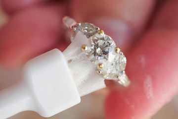 Jeweller hand cleaning and polishing vintage jewelry diamond ring closeup macro