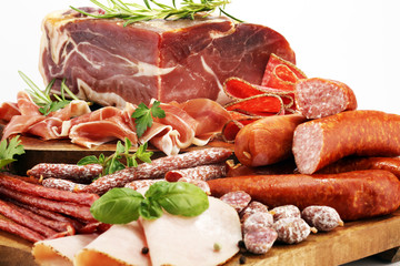 Food tray with delicious salami, pieces of sliced ham, sausages,salad and vegetable. Meat platter with selection