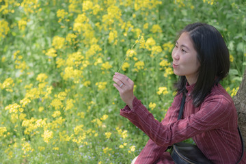 Naklejka na ściany i meble Unspecific woman looking at the yellow flower in her hand at the east lake park.
