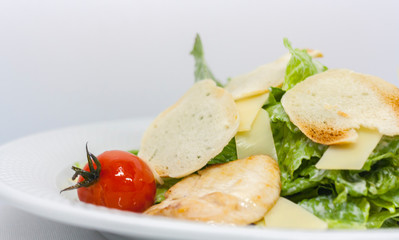 Fototapeta na wymiar Caesar salad with croutons, cheese, lettuce and pickled tomatoes on a white background close-up