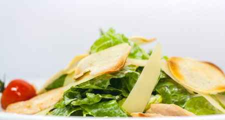 Caesar salad with croutons, cheese, lettuce and pickled tomatoes on a white background close-up