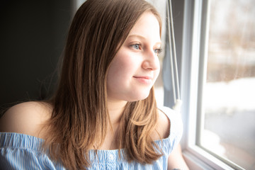 Portrait of a beautiful young teenager girl near window