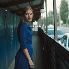 Fototapeta premium Beautiful blond hair girl posing in blue shirt at the city