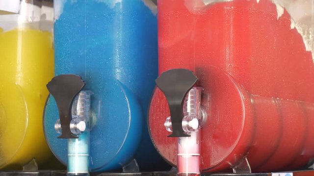 Working slush machines with colourful frozen drinks inside.