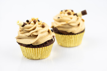 Two great and delicious muffins decorated with caramel foam and sweet tube. Isolated on white background.