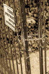 Gate closed with a chain , with a plaque saying 'private property no trespassing' in polish