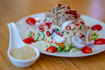 Spicy tuna salad In a white plate, salad this dish consist of tuna, lettuce, chinese cabbage, carrot onion red chilli rough cut, and tomato half cut Used to arrange dishes dressing in a spoon ceramic.