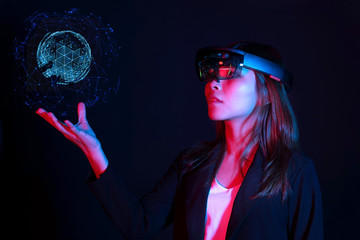 Business woman try vr glasses hololens in the dark room. Young asian girl experience ar with glow earth globe on hand. Future technology concept - obrazy, fototapety, plakaty