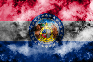 The national flag of the US state Missouri in against a gray smoke on the day of independence in different colors of blue red and yellow. Political and religious disputes, customs and delivery.