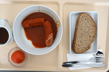 Curry sausage with bread for dinner in a canteen