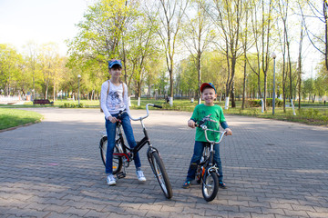 happy boy and girl ride bicycles in the park.