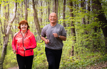 Husbanf and wife wearing sportswear and running in forest