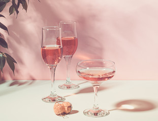 Champagne or wine in various elegant glasses on a pink background bright light. Copy space. S Horizontal frame. Toning