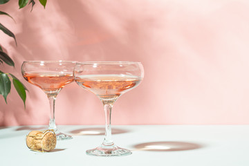 Champagne or wine in elegant glasses on a pink background bright light. Copy space. Selective focus.