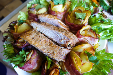 Grilled pork ribs on a white plate with greens, lettuce and meat rolls