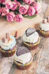 Handmade chocolate muffins with decorations. Book and a bouquet of roses