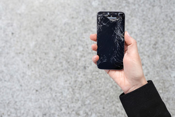 Smartphone with a broken screen glass in hand of young woman