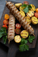 Closeup of grilled chicken kebabs with roasted potato, cherry tomatoes and fresh parsley, selective focus