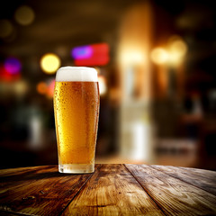 Fresh cold beer in glass and free space for your bottle. Bar interior background 