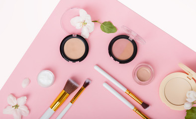 Face care and make up products with spring apple bloom (tonic or lotion, serum, cream, micellar water, cotton pads and makeup brushes) on pink background. Freshness and face care. Decorative cosmetics