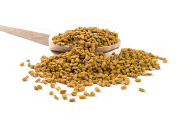fenugreek seeds on wooden spoon on white background