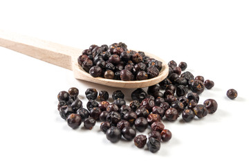 juniper berries on wooden spoon on white background