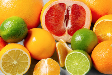group of whole and sliced citrus fruits - tangerines, lemons, limes, oranges, grapefruits on the surface of the table - image
