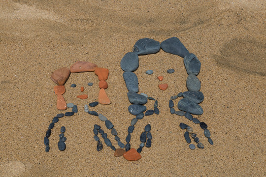 drawing a picture with stones of mother's day on sand on the beach.