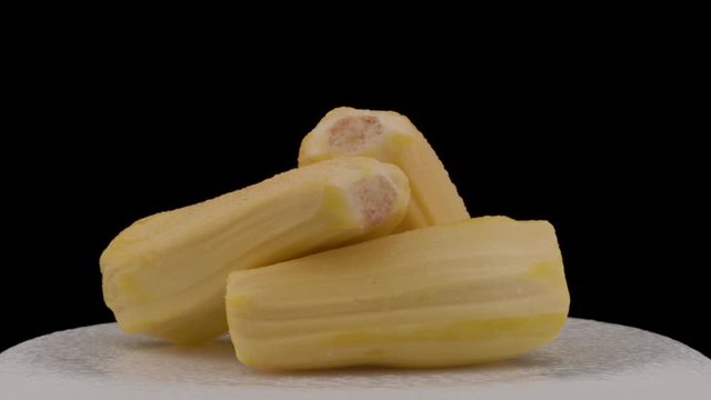 A close-up shot of a tropical kathal fruit slices rotating on the turntable. Isolated on the black background. Wonders of nature, exotic food concept