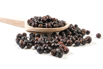 juniper berries on wooden spoon on white background