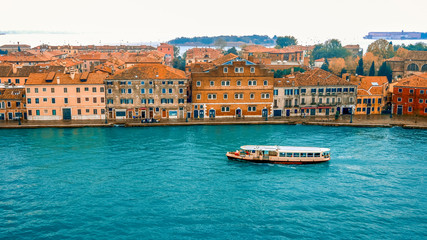 Cityscape of Venice and vaporetto from ship entering port through the Venetian Lagoon, Italy