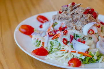 Spicy tuna salad In a white plate, salad this dish consist of tuna, lettuce, chinese cabbage, carrot onion red chilli rough cut, dressing and tomato half cut Used to arrange dishes.
