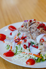 Spicy tuna salad In a white plate, salad this dish consist of tuna, lettuce, chinese cabbage, carrot onion red chilli rough cut, dressing and tomato half cut Used to arrange dishes.