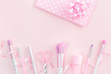 Feminine accessories with unicorn makeup brushes on pink background and a polka dot festive gift envelope. Flat lay with copy space, birthday beauty and cosmetics blogger concept