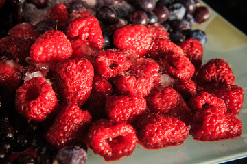 closeup frozen thawed red raspberries and blueberries