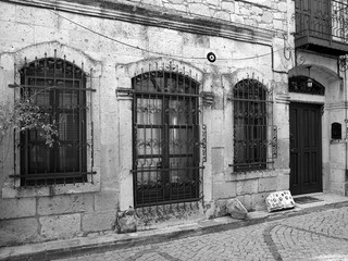 Schöne alte Fassade mit vergitterter Tür und Fenster in den Gassen der Altstadt von Alacati bei...