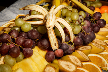 assortment of grapes and sliced tropical fruits on big plate